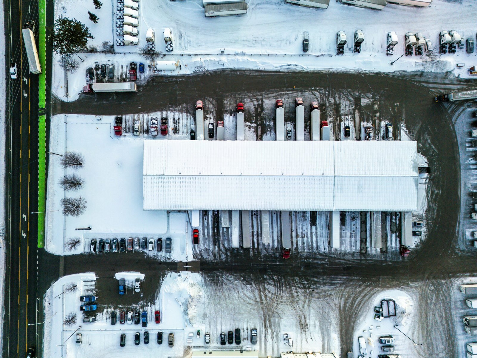 Aerial view of a snowy industrial warehouse site with trucks